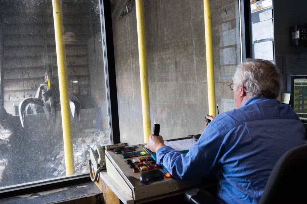 man operating crane at waste management facility